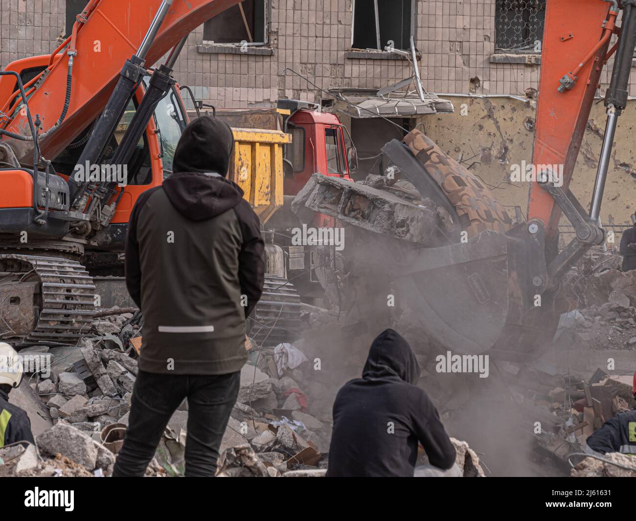 Borodyanka, Ukraine - April 2022: Bulldozer clears debris in search of people injured by air bombings. Bombed houses of civilians in the Urkain cities. Consequences of bombings in Ukrainian war 2022. Stock Photo