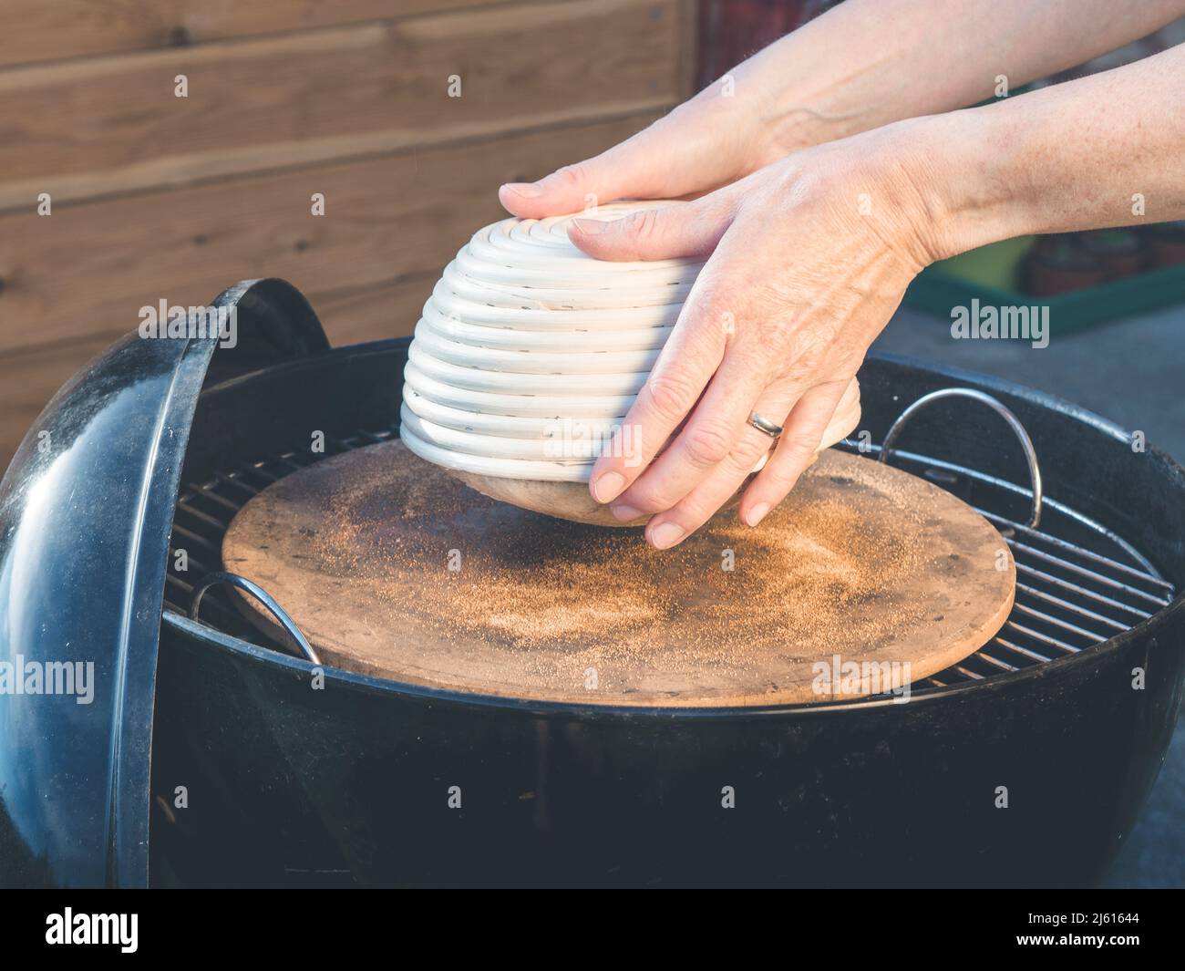image shows how to bake homemade crunchy bread on a charcoal grill; hand holding wooden wicker