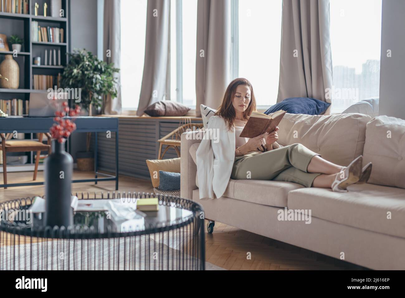 Woman relaxing on sofa and reading book Stock Photo - Alamy