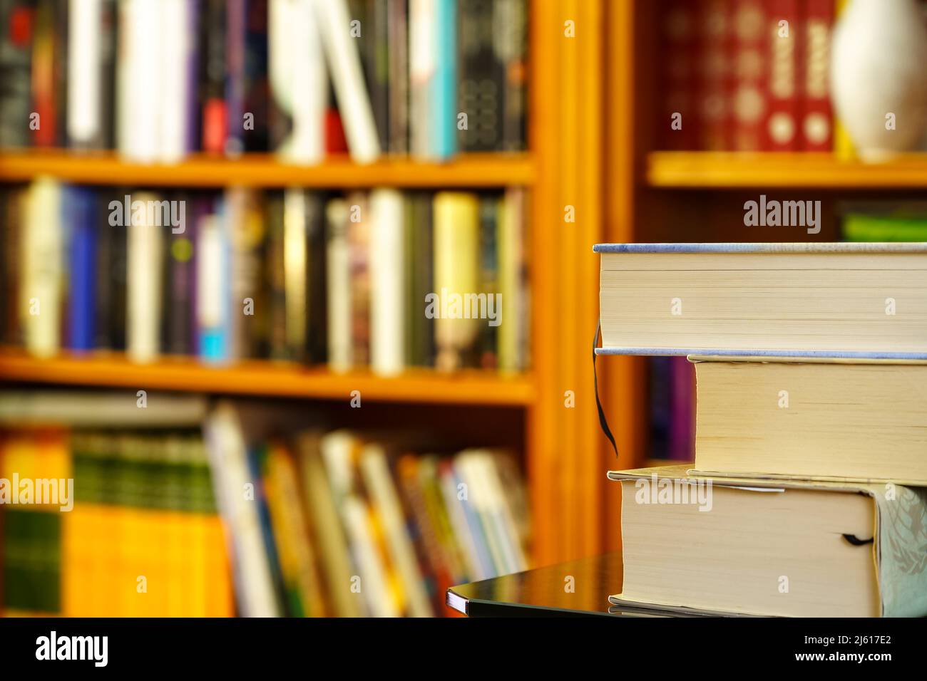 library with lots of books to read, computer on shelves. Stacked books in the foreground. Copy space. Background. Stock Photo