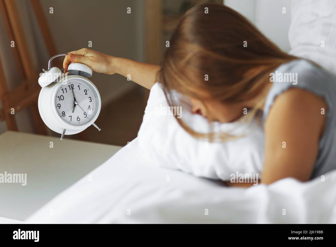 Woman sleep on the bed turns off the alarm clock wake up at the morning, Selective focus.Young woman reaching to turn off alarm clock ,early morning Stock Photo