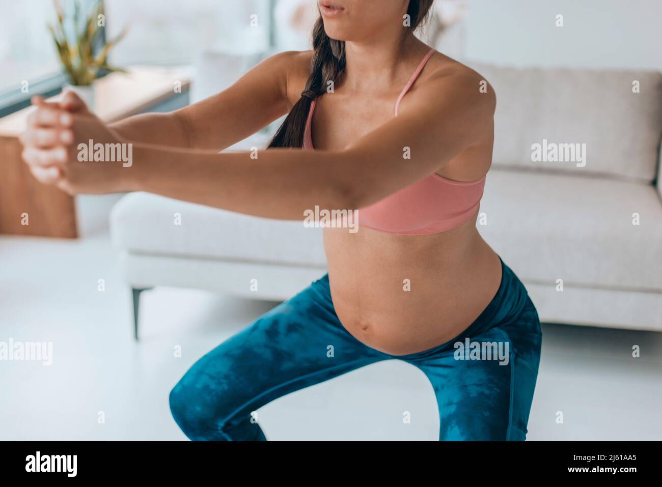 Pregnancy workout woman doing squat glutes exercises at home. Prenatal fitness training for pregnant women Stock Photo