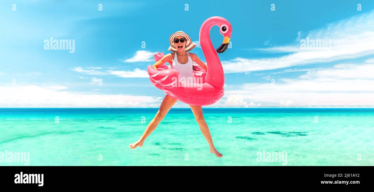 Vacation beach woman jumping of joy with pink flamingo pool float for summer holidays on ocean banner background. Fun travel excited girl for luxury Stock Photo