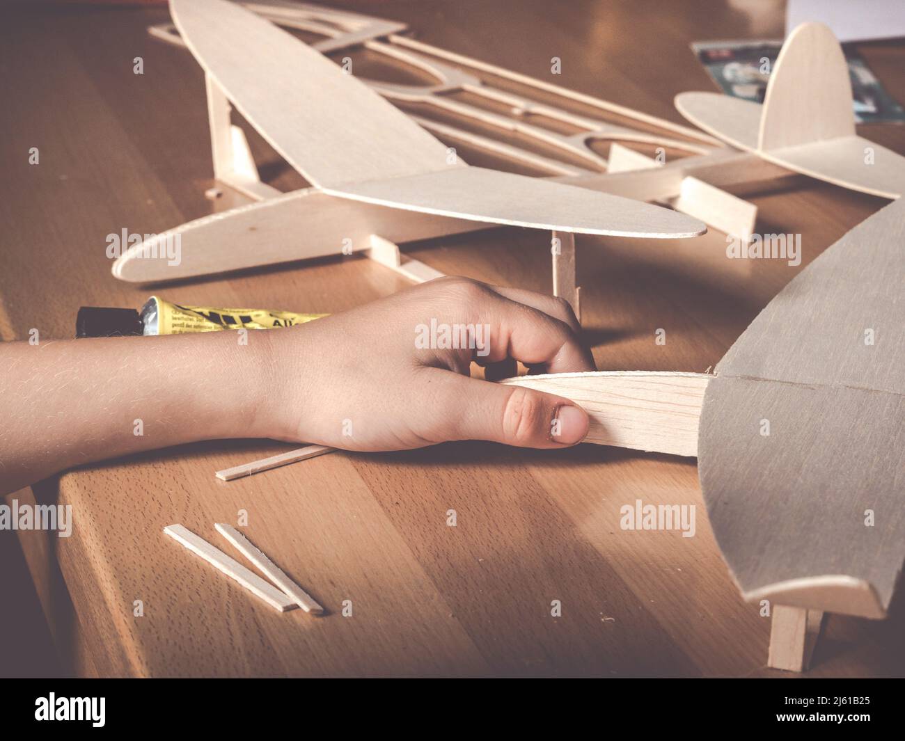 image shows a balsa wood aircraft model and kids hand holding a second wooden flight model Stock Photo