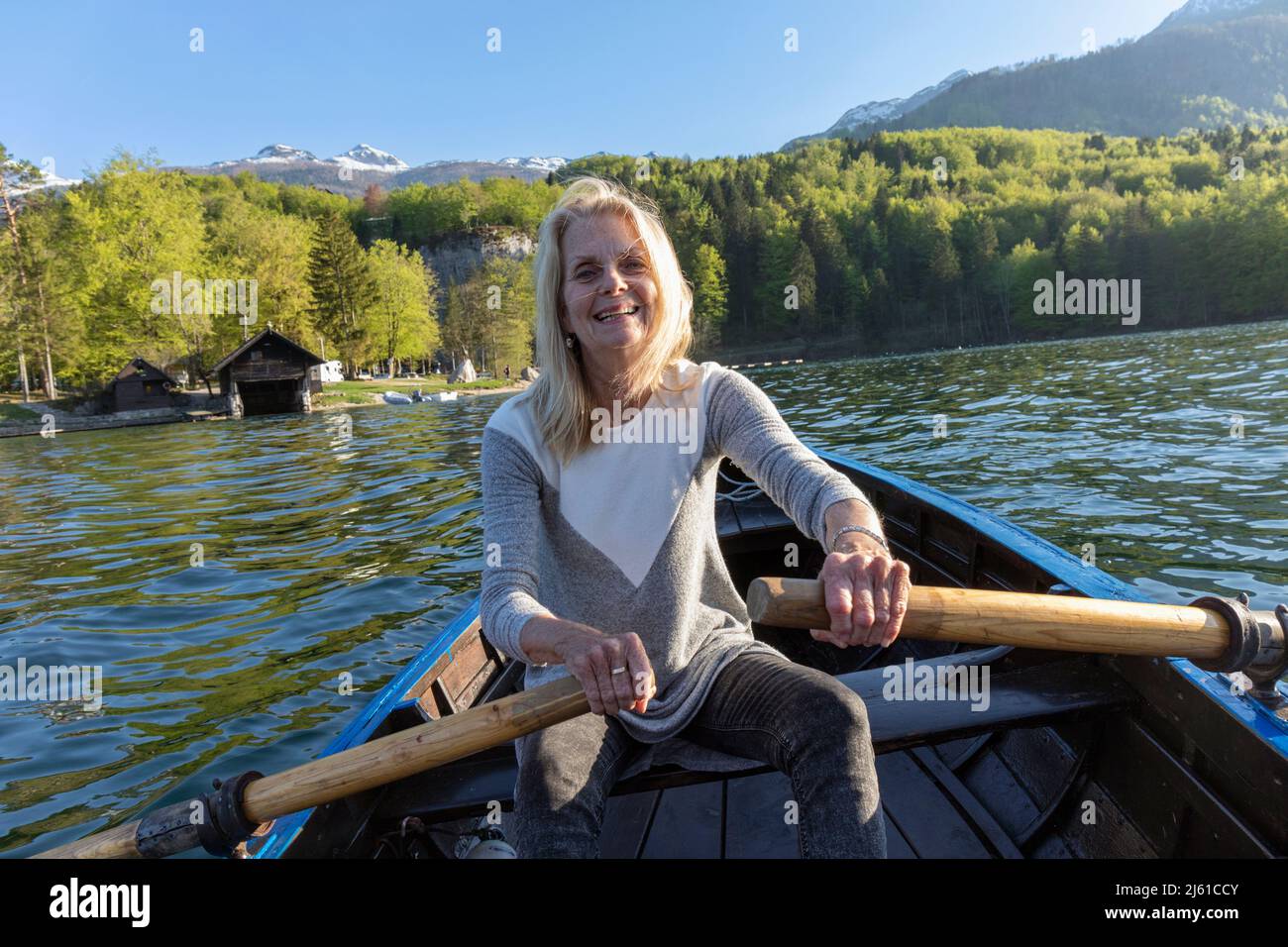 Lake Bohinj (Bohinjsko jezero), Triglav National Park, Upper Carniola, Slovenia.  Woman rowing on the lake.  Julian Alps in background.  MODEL RELEASE Stock Photo