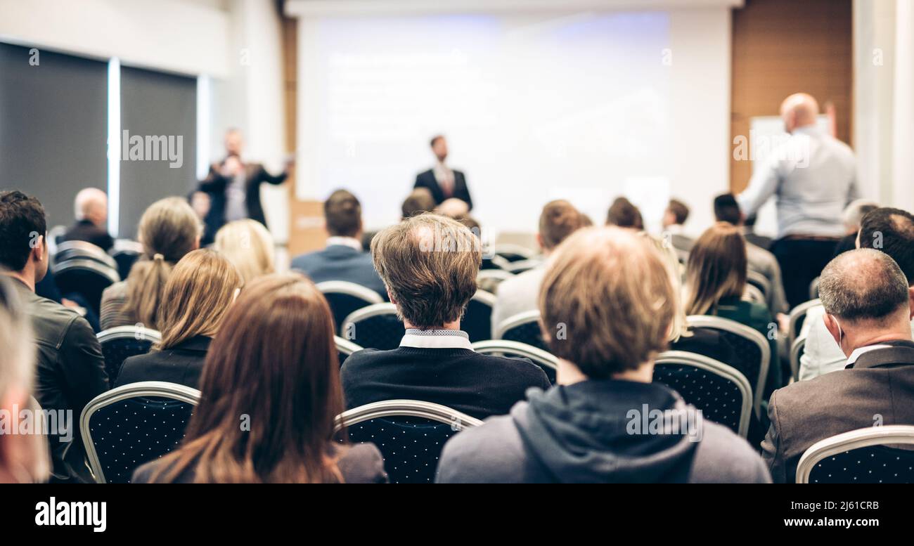 I have a question. Group of business people sitting in conference hall. Businessman raising his arm. Conference and Presentation. Business and Stock Photo