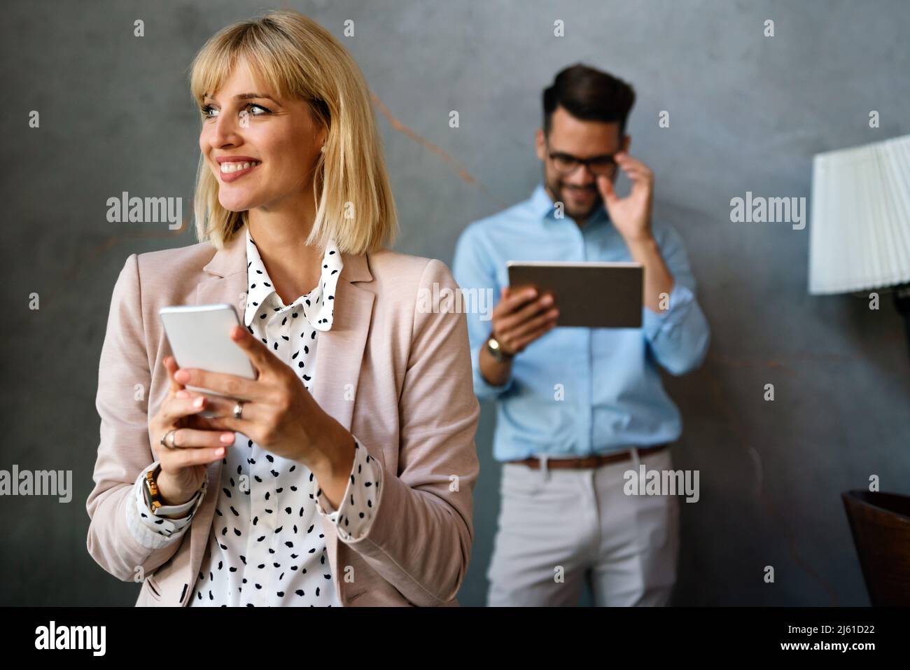 Beautiful successful businesswoman checking emails on the phone in modern office i Stock Photo