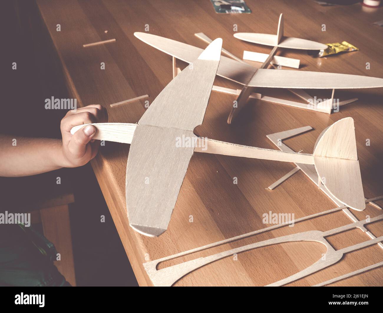 boys hand holding selfmade wooden airplane model Stock Photo