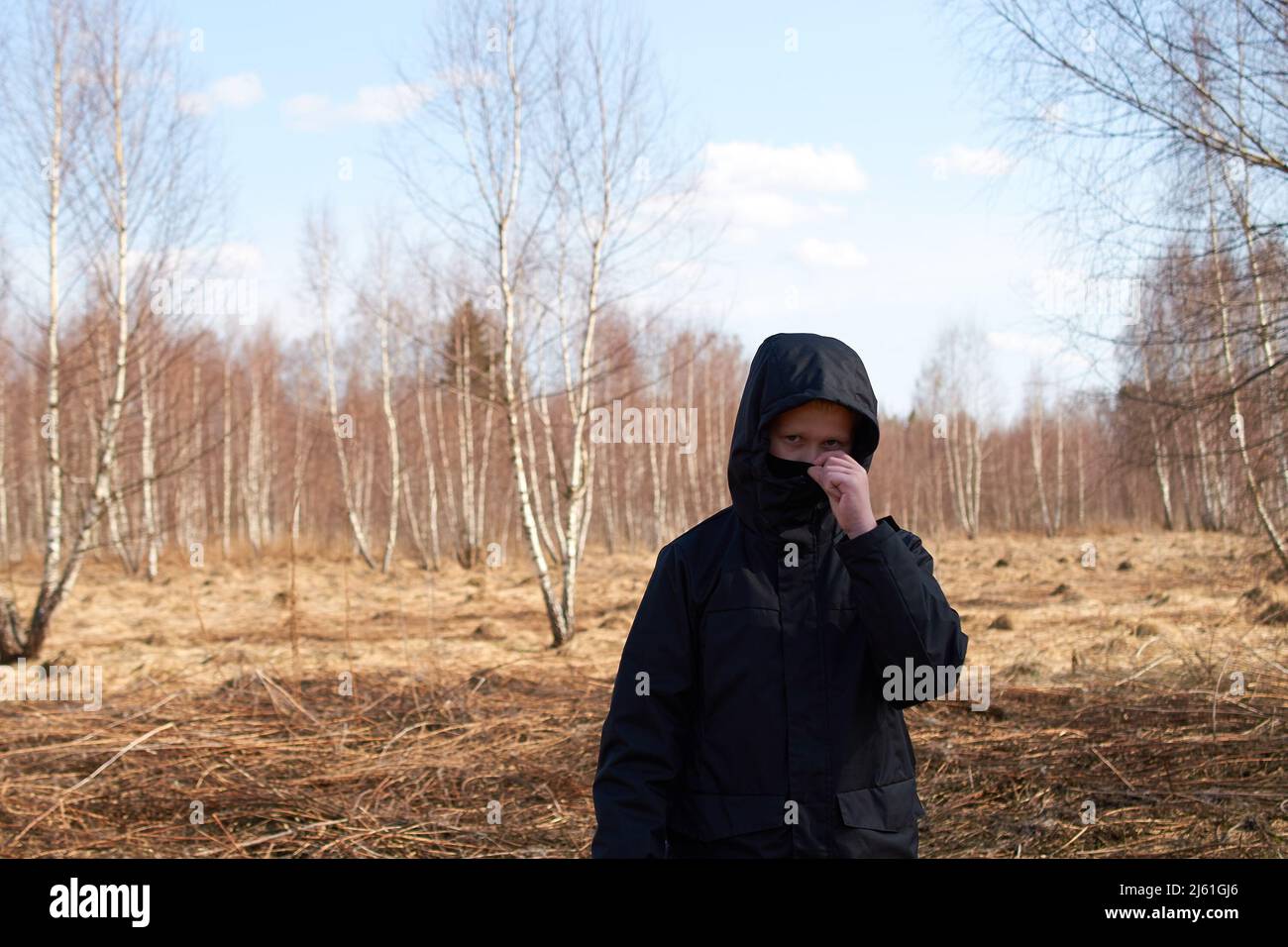 A European preteen in a black hooded jacket and a black mask Stock Photo