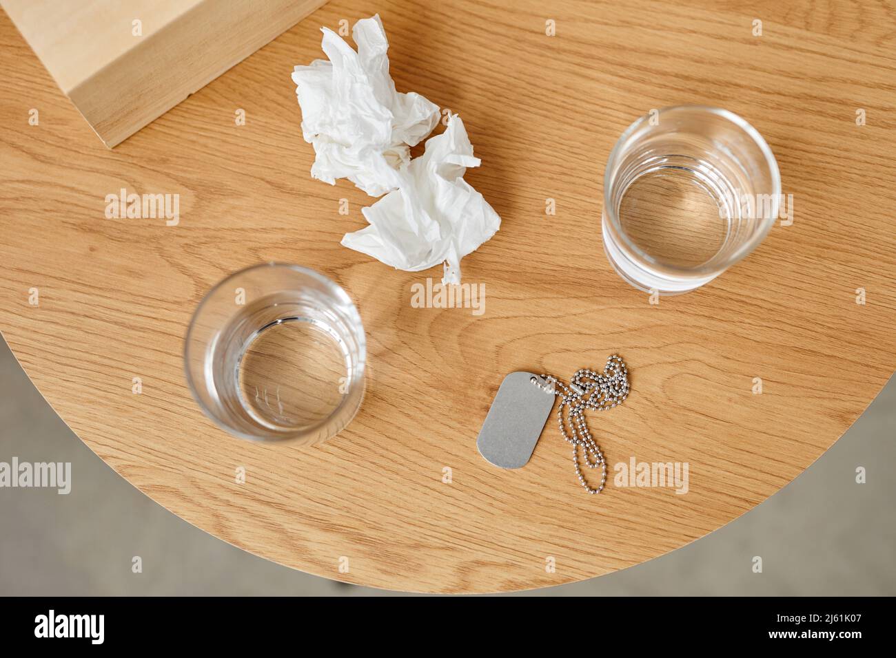 Top-down still life shot of used paper napkins, glasses with water and military dog tag on table, PTSD treatment concept Stock Photo