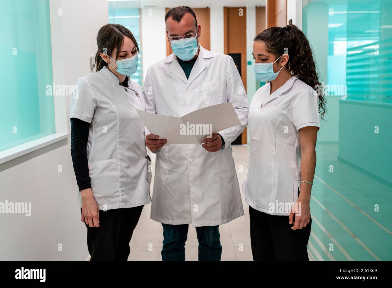Doctor and nurses wearing protective face masks analyzing medical ...