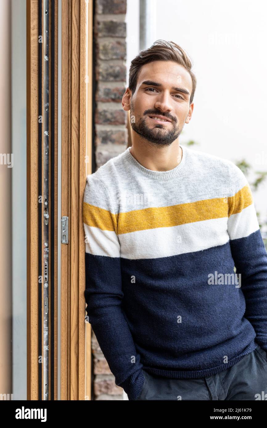 Man with hands in pockets leaning on door frame Stock Photo Alamy