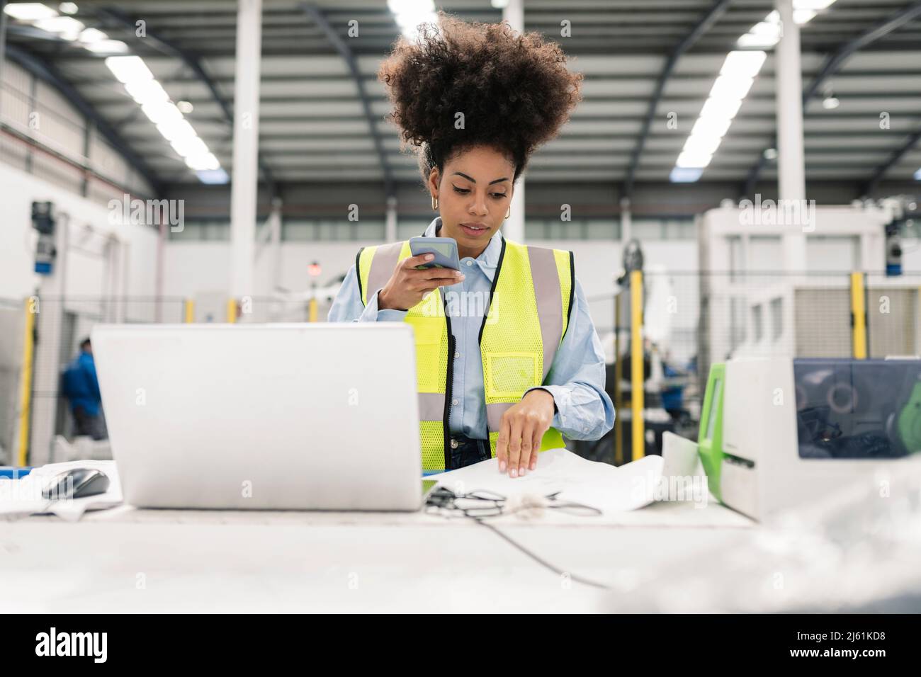 Engineer talking on mobile phone through speaker examining documents in factory Stock Photo