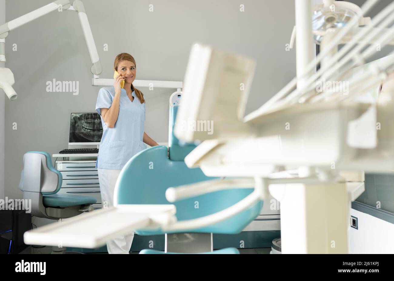 Dentist talking on smart phone at medical clinic Stock Photo