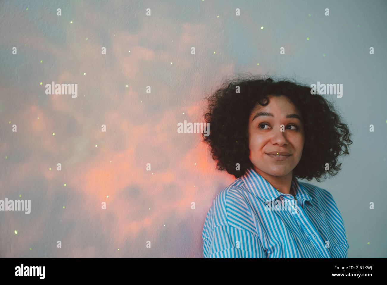 Smiling woman looking at astro light effect falling on wall Stock Photo