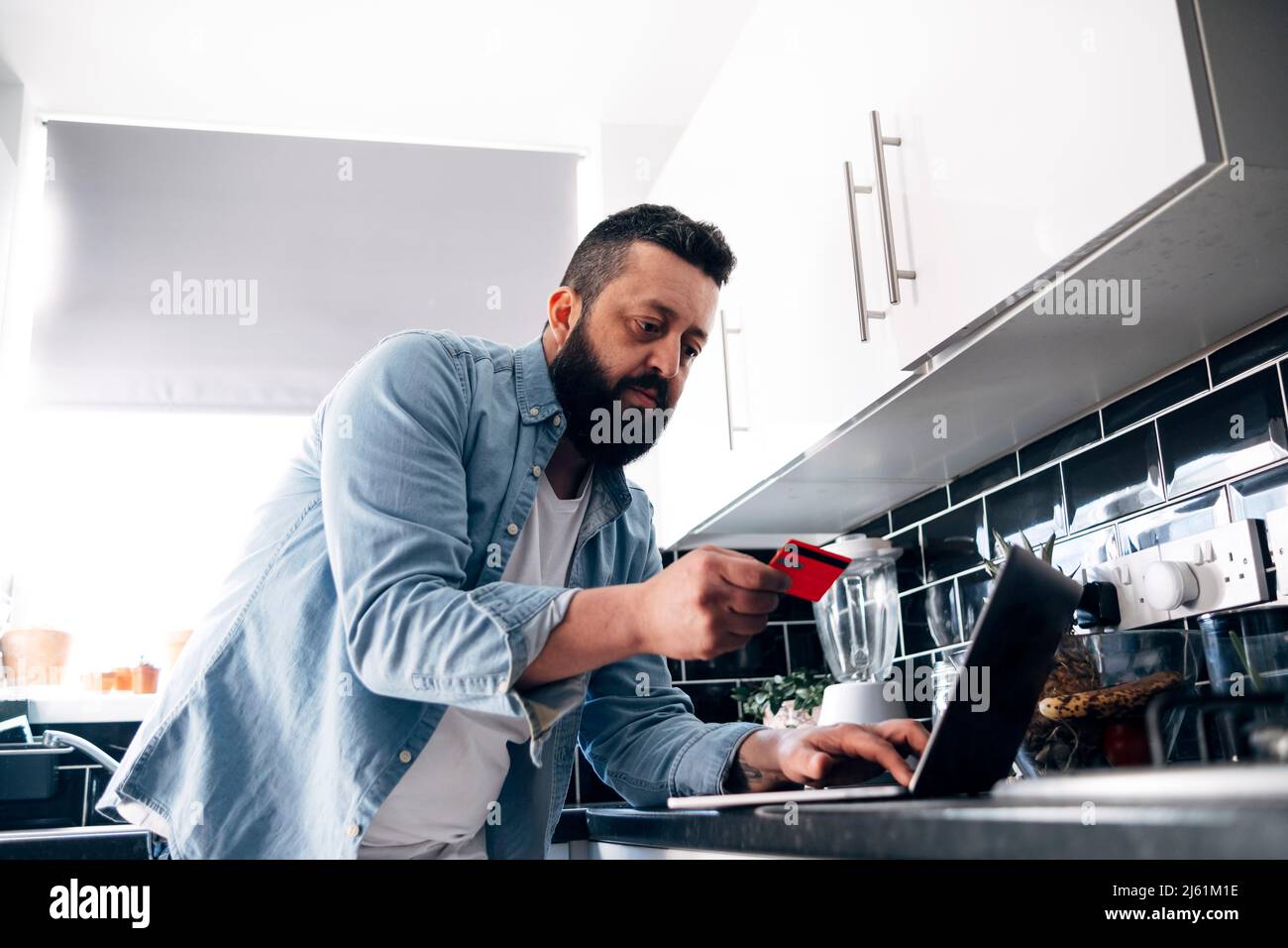 Man with credit card paying financial bill through laptop at home Stock Photo