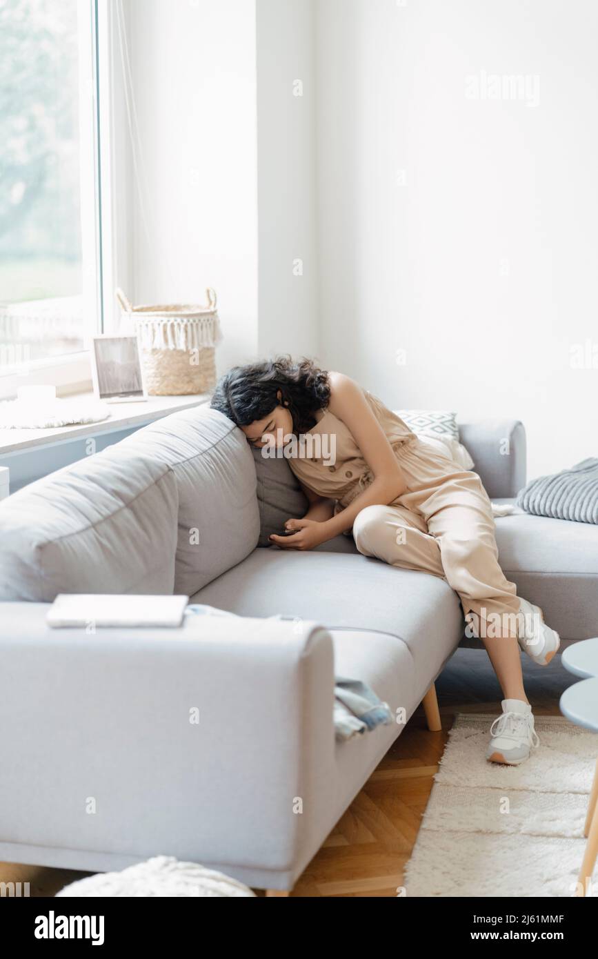 Teenage girl using mobile phone sitting on sofa at home Stock Photo - Alamy