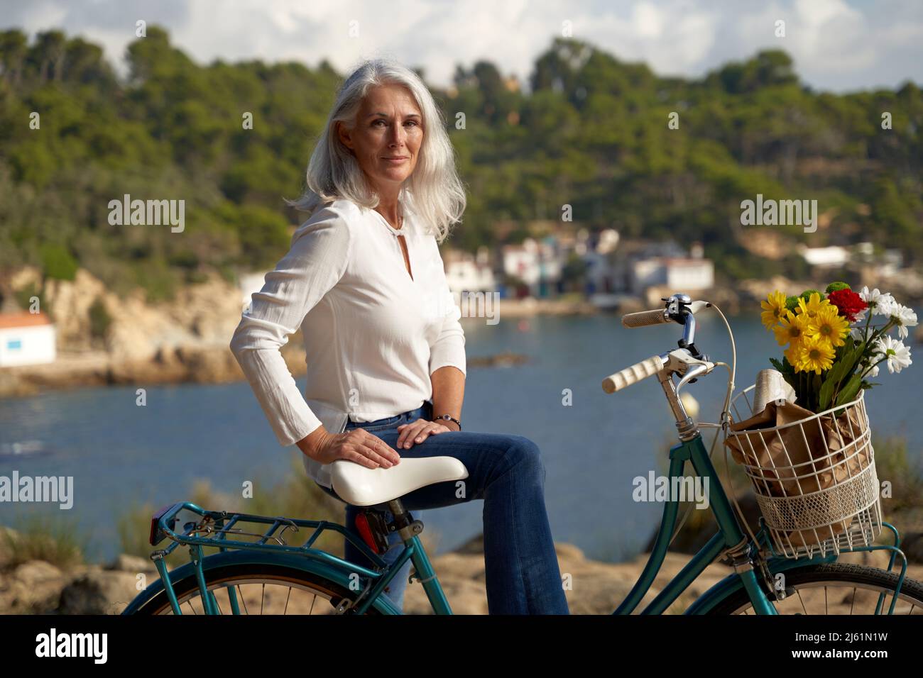 Smiling woman with bicycle on sunny day Stock Photo