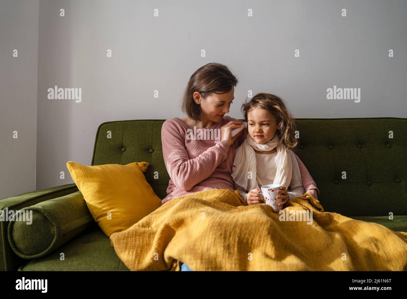Mother taking temperature of sick daughter with thermometer at home Stock Photo