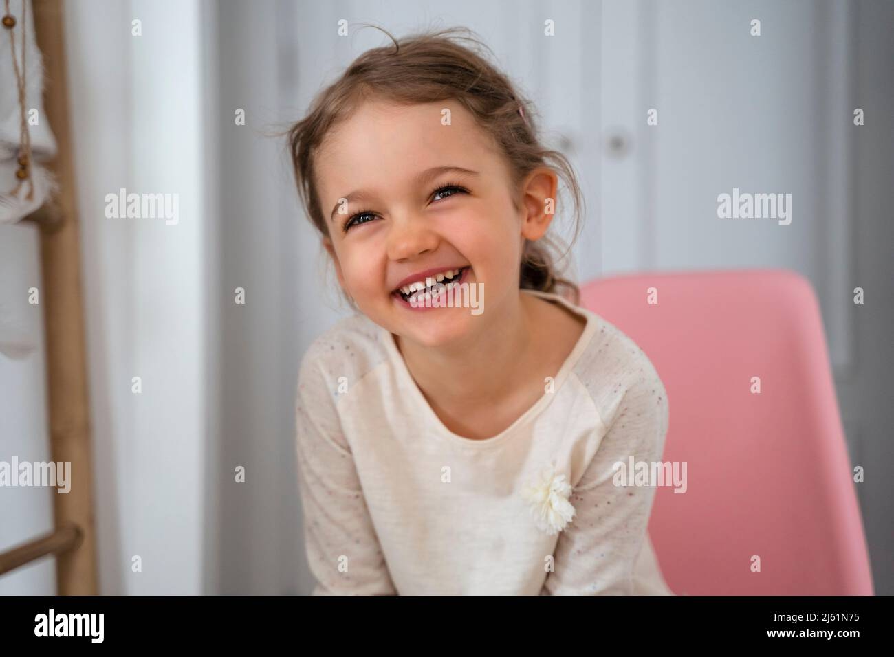 Happy cute girl sitting on chair at home Stock Photo - Alamy