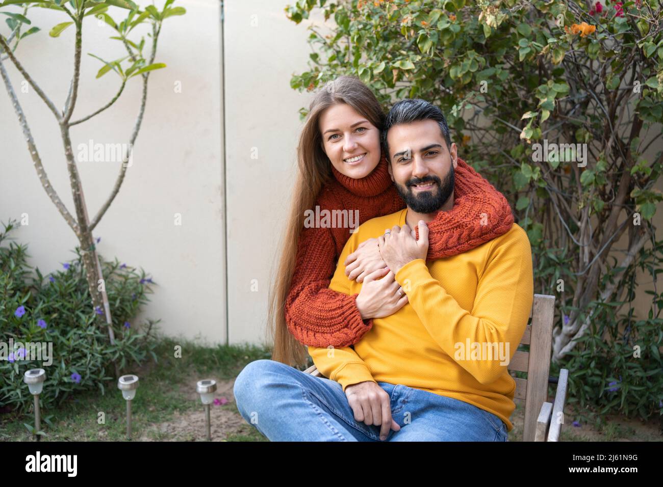 Happy woman hugging man from behind in garden Stock Photo