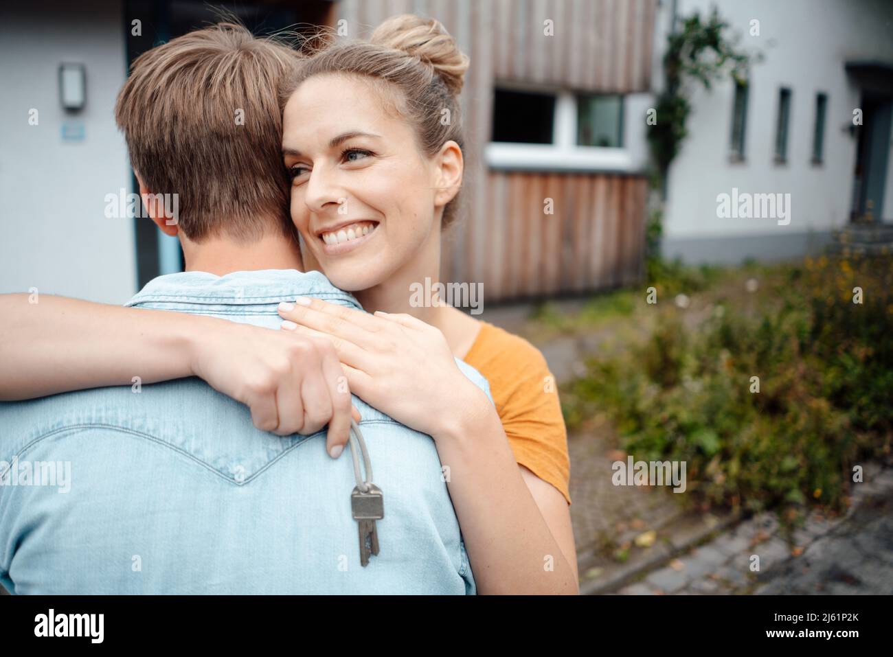 Happy blond woman holding house key hugging boyfriend at backyard Stock ...