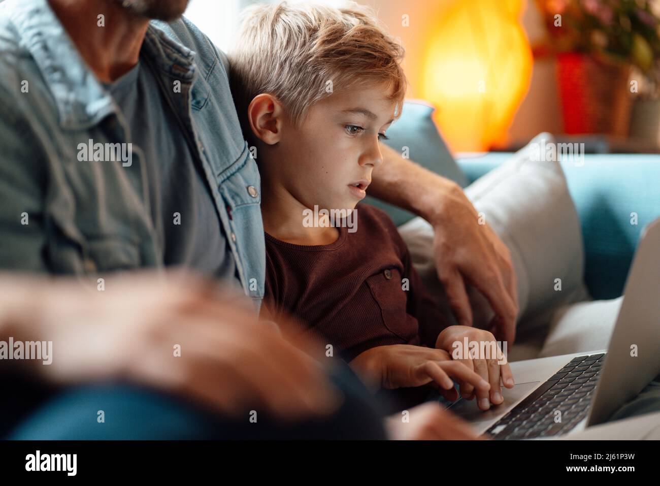 Boy using laptop sitting by parents at home Stock Photo - Alamy