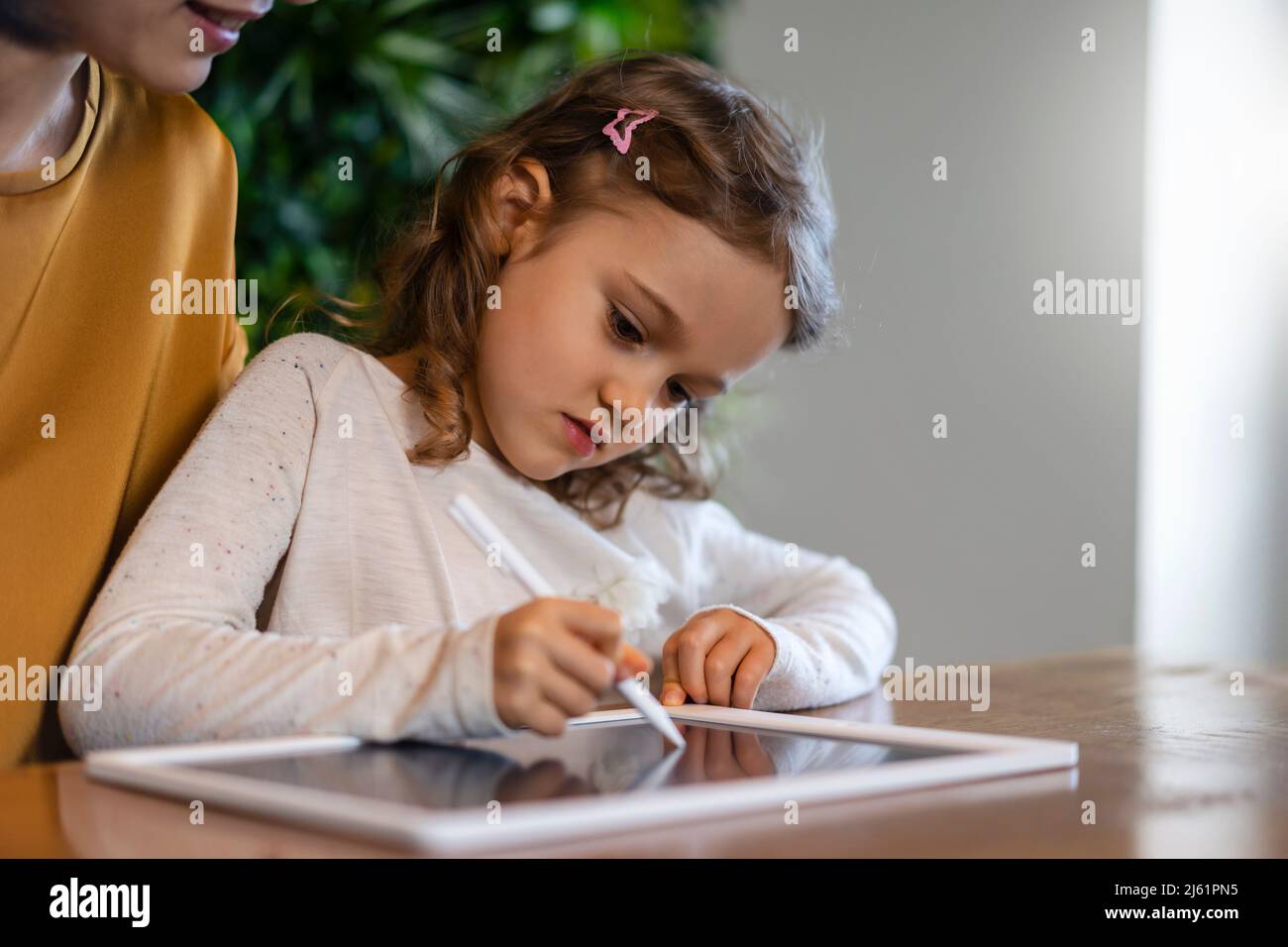 Cute girl writing on tablet PC with digitized pen at home Stock Photo