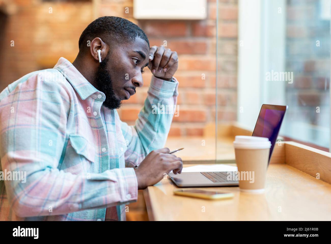 Freelancer using laptop sitting at cafe Stock Photo