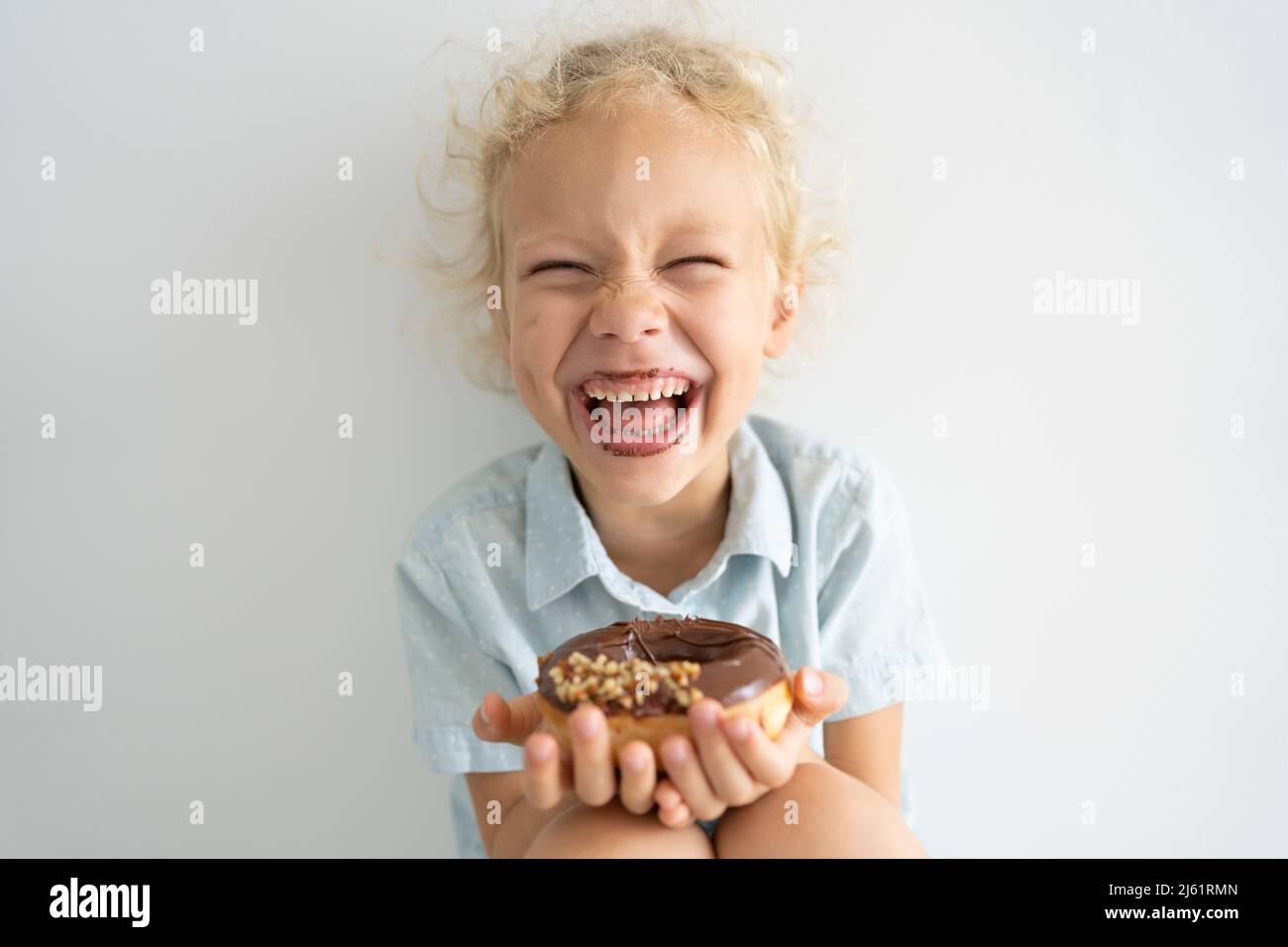 Cheerful girl holding doughnut and laughing Stock Photo
