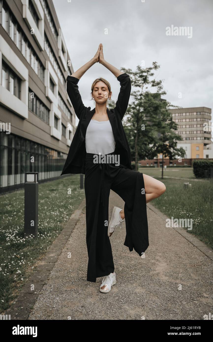 Young woman practicing tree pose yoga on footpath Stock Photo - Alamy