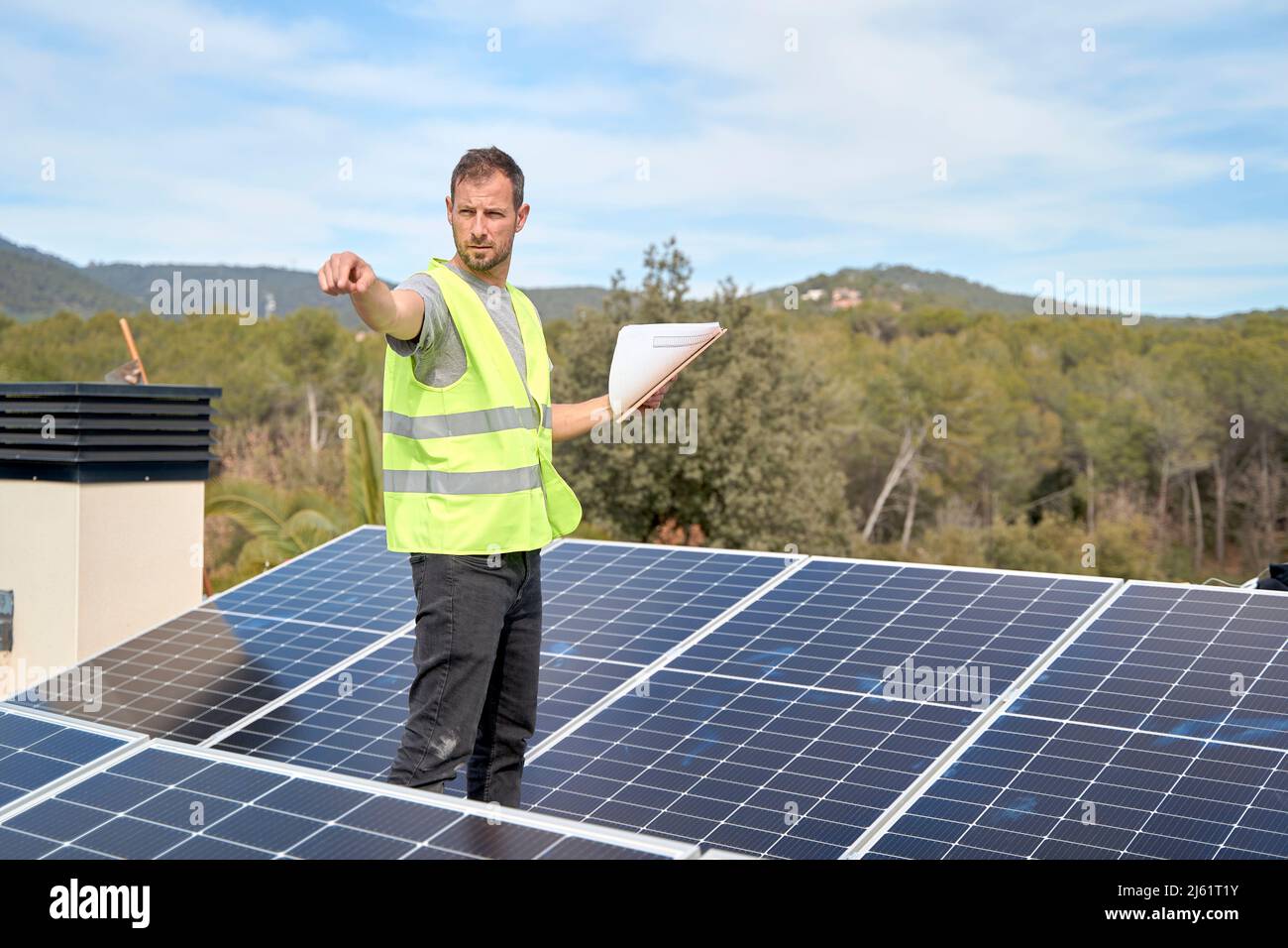 Engineer with blueprint pointing amidst solar panels at rooftop Stock ...