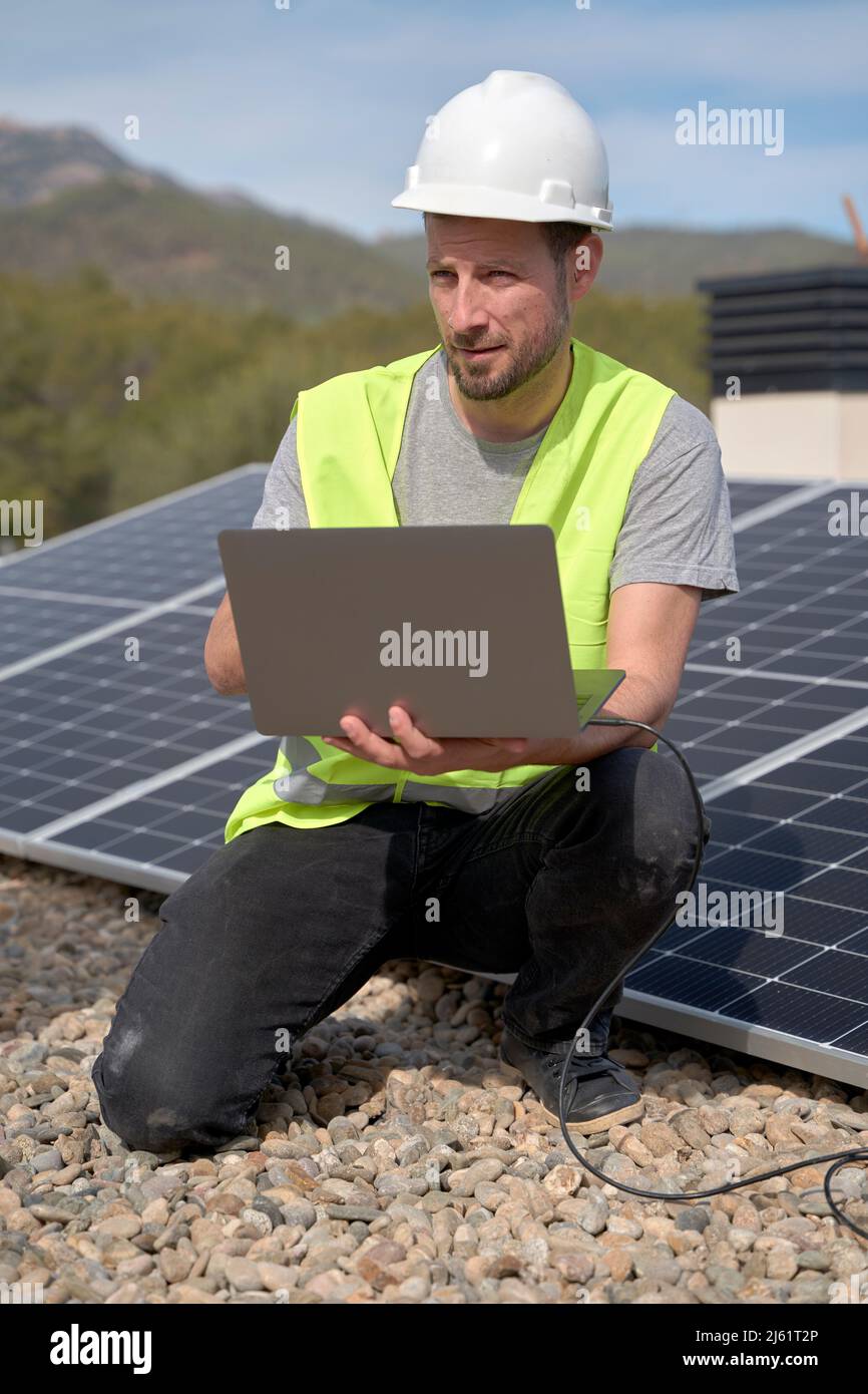Engineer with laptop installing solar panels on sunny day Stock Photo ...
