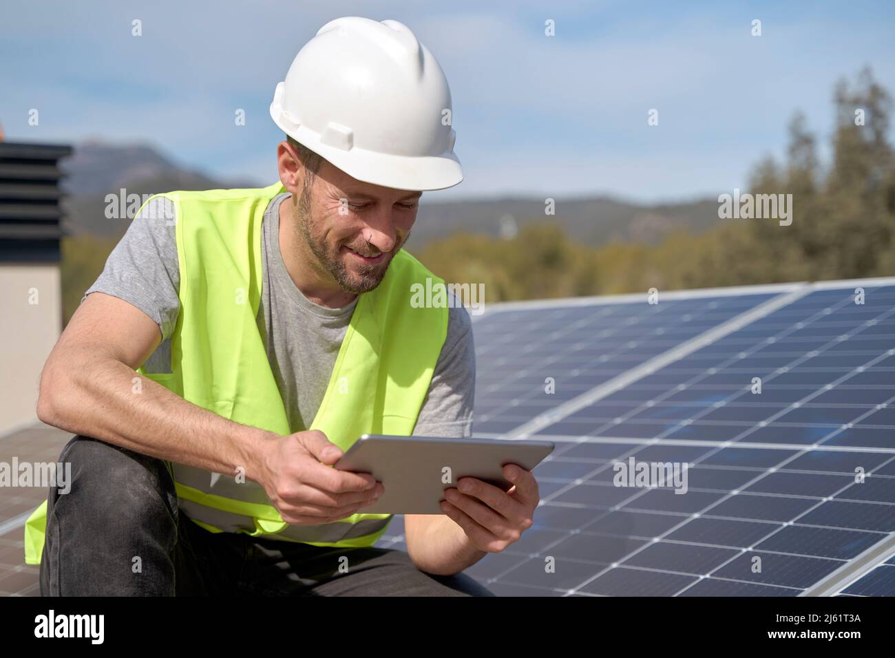 Smiling engineer using tablet PC by solar panels on sunny day Stock Photo