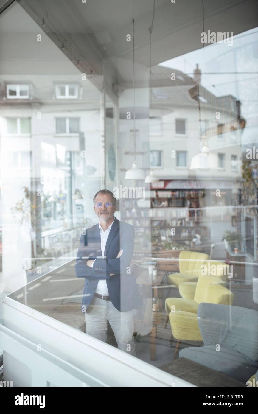 Businessman with arms crossed seen through glass window Stock Photo - Alamy