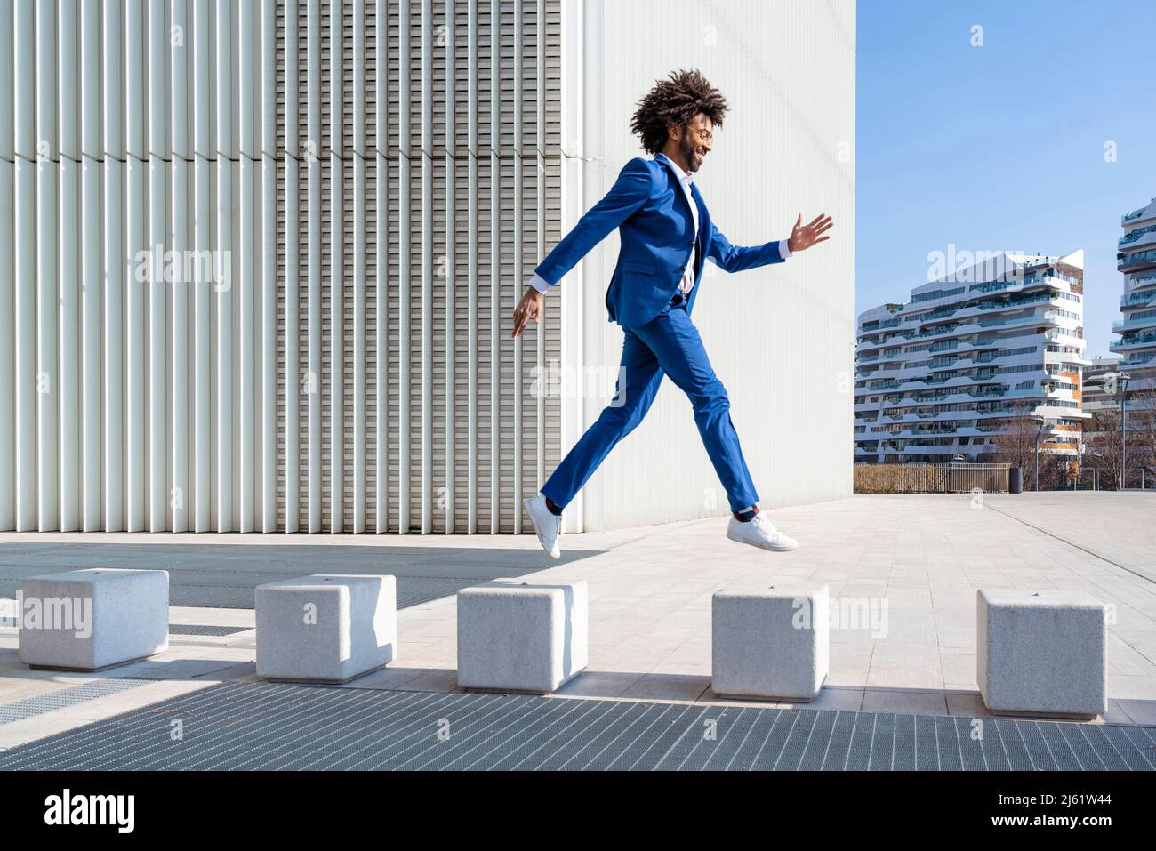 Playful businessman jumping on concrete block Stock Photo Alamy