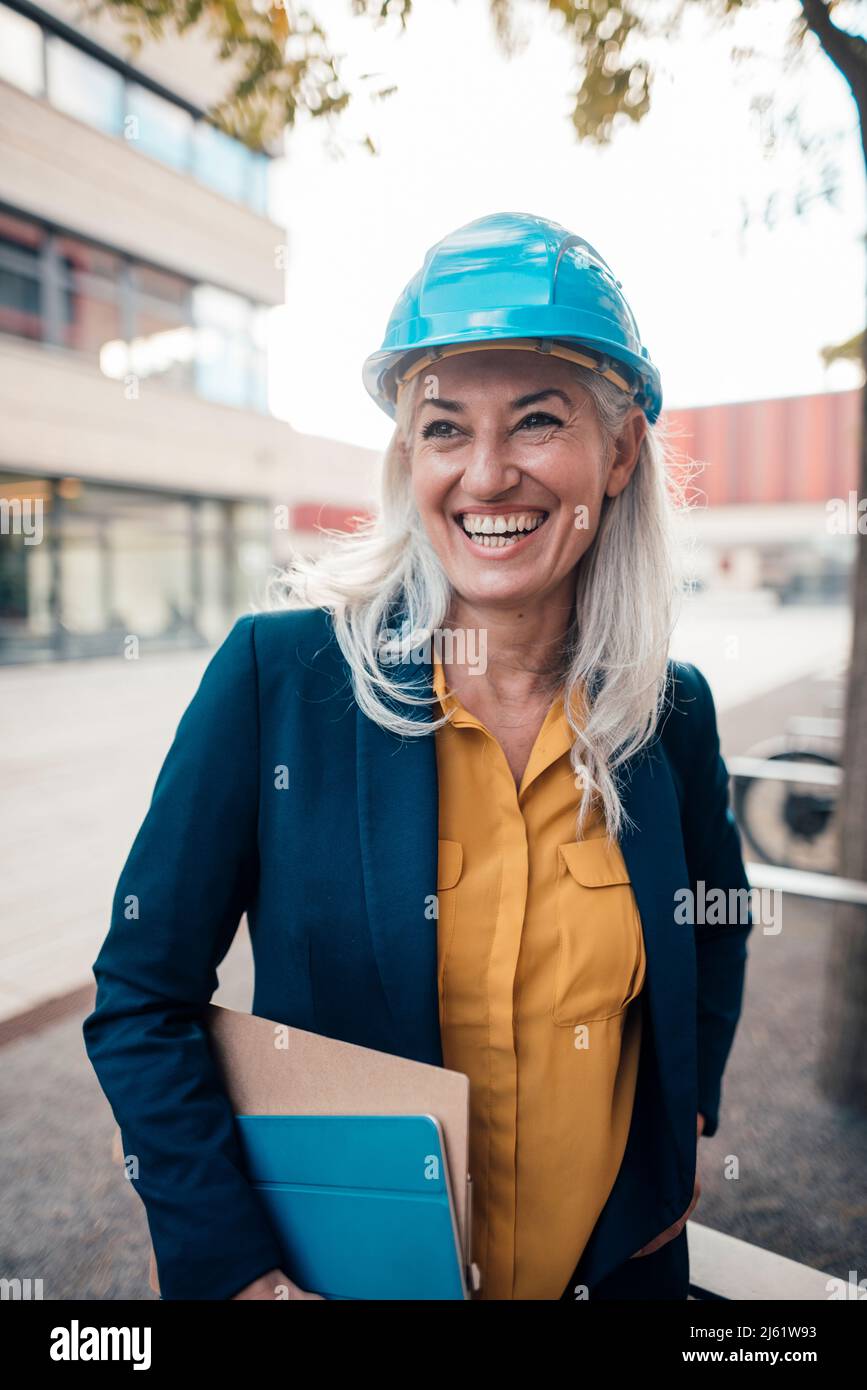 Cheerful engineer wearing with clipboard standing at office park Stock Photo