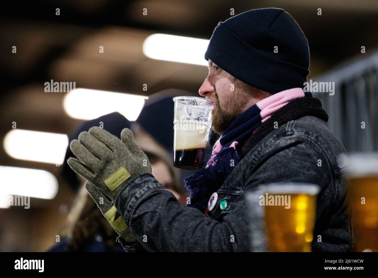 Man applauding at a football match holding a beer in his mouth. Stock Photo
