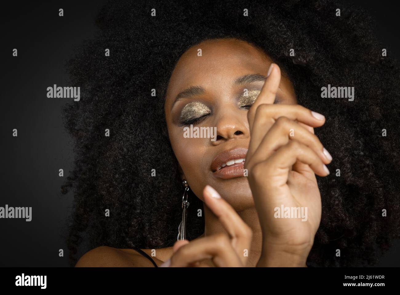 Beautiful young woman with eyes closed against black background Stock Photo