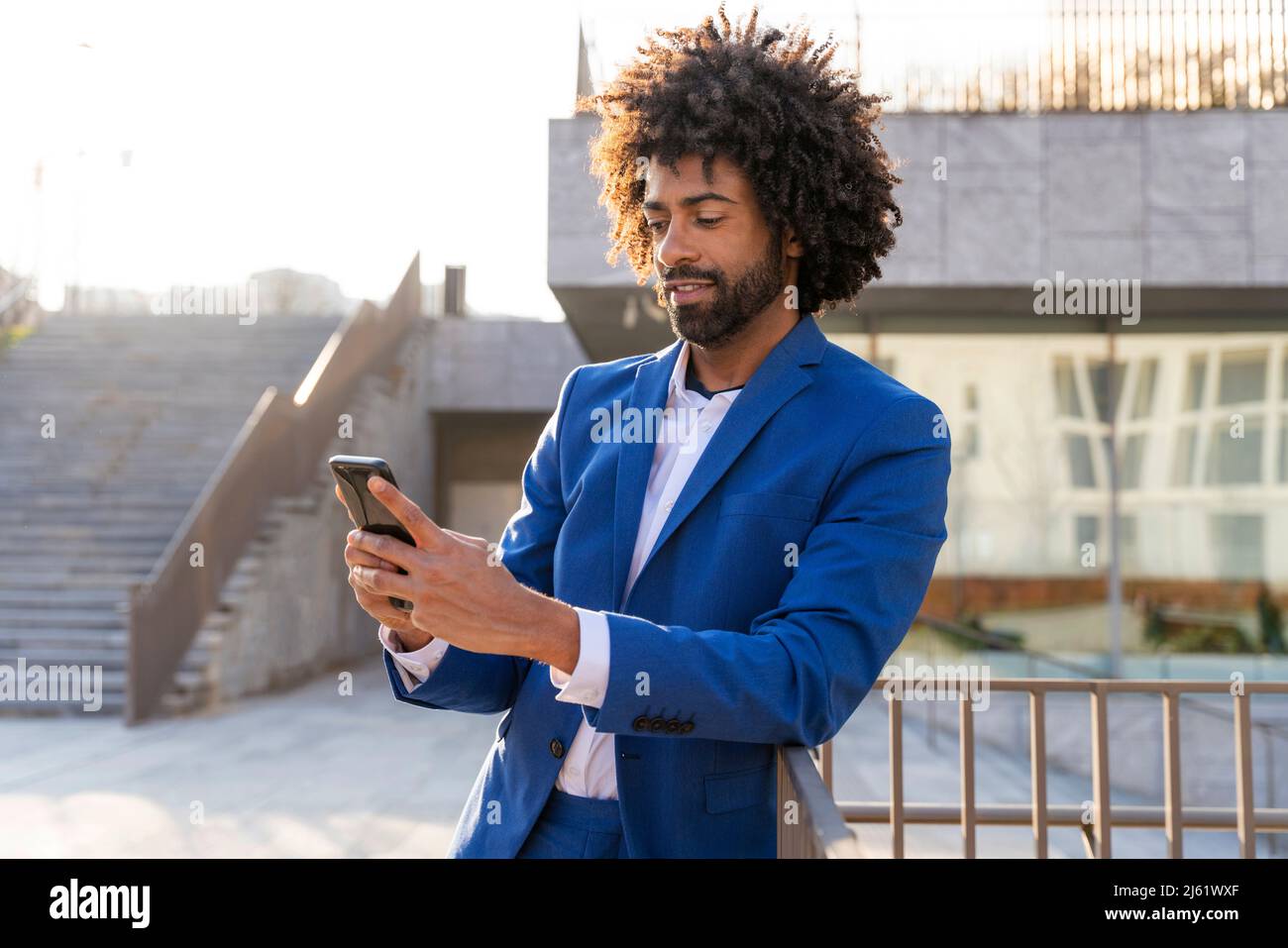 Businessman using mobile phone leaning on railing Stock Photo