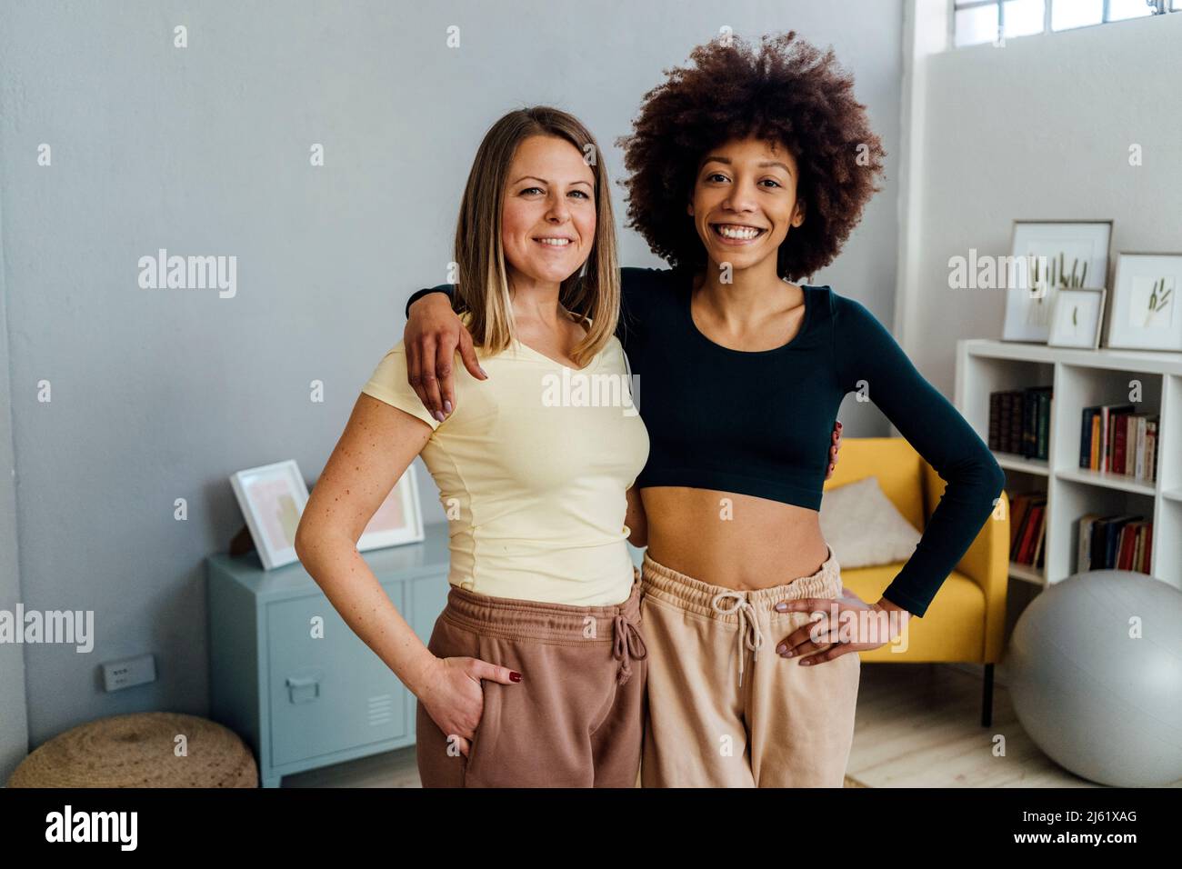 Smiling women standing with hands in pockets at home Stock Photo - Alamy