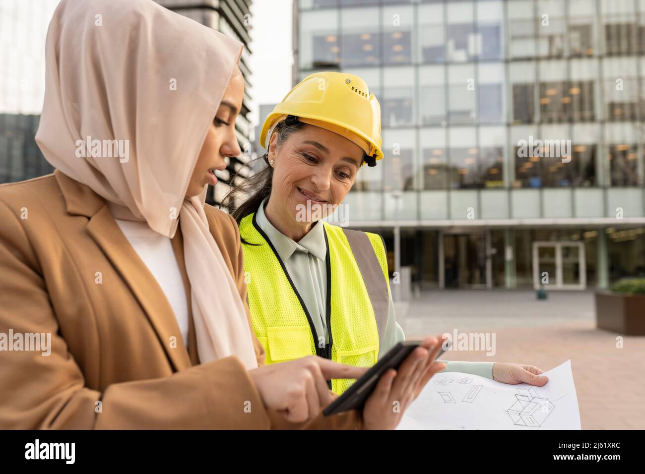 Smiling Engineer Smiling engineer wearing hardhat looking at businesswoman discussing ...