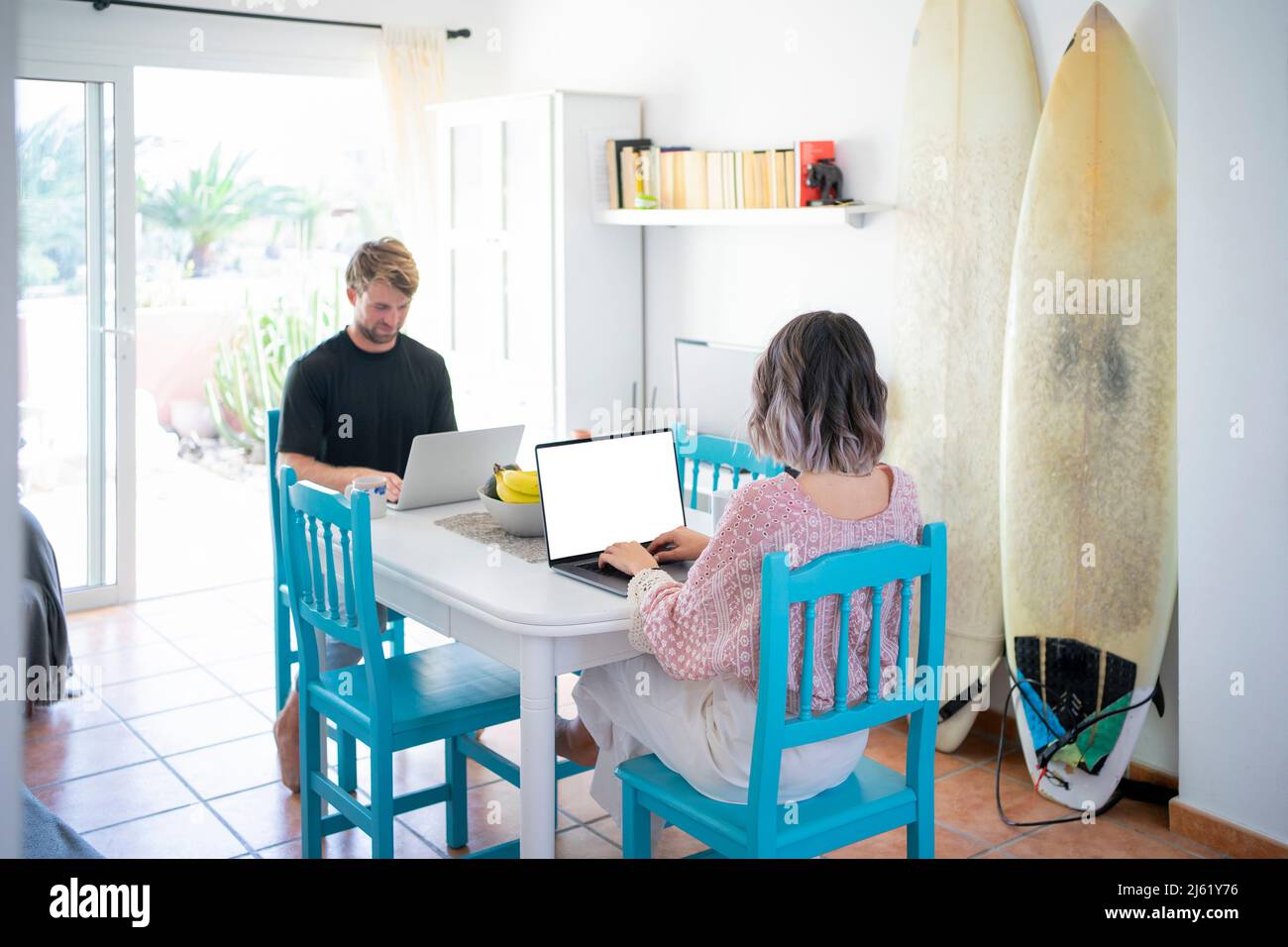 Freelancers using laptops sitting at dining table working from home Stock Photo