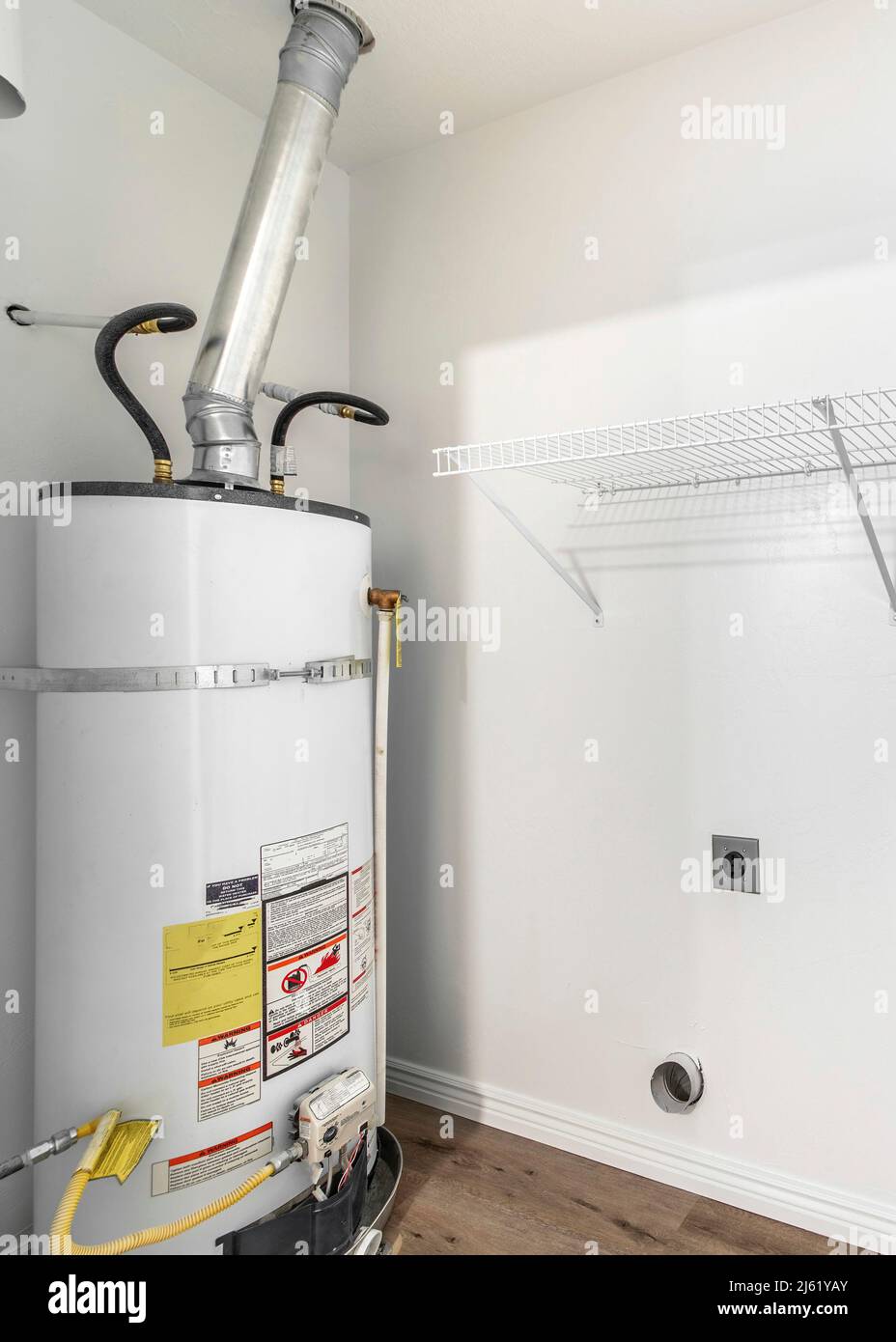 Vertical Empty white laundry room with water heater tank and wall mounted  wire shelf Stock Photo - Alamy