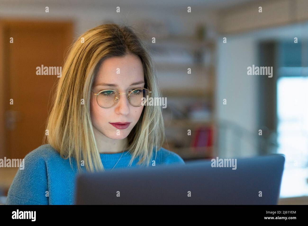 Young blond woman using laptop sitting at table Stock Photo