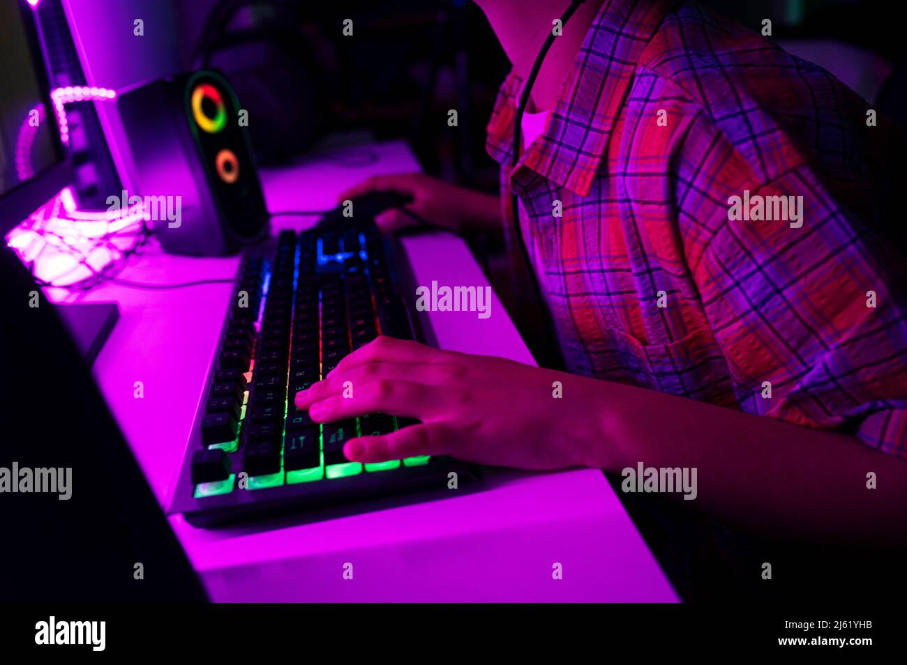 Boy with computer keyboard playing game sitting at table Stock Photo