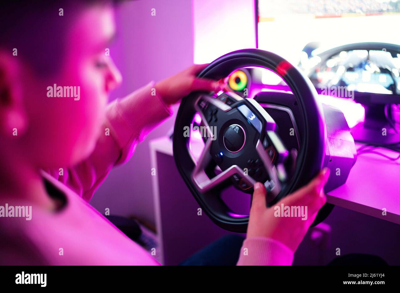 Boy playing video game with steering wheel simulator at home Stock