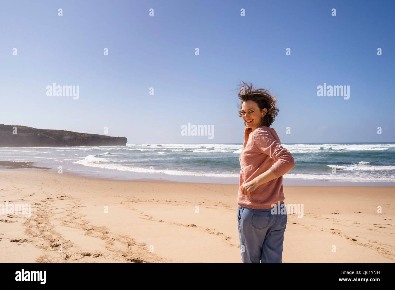 Happy woman running towards sea at beach on sunny day Stock Photo