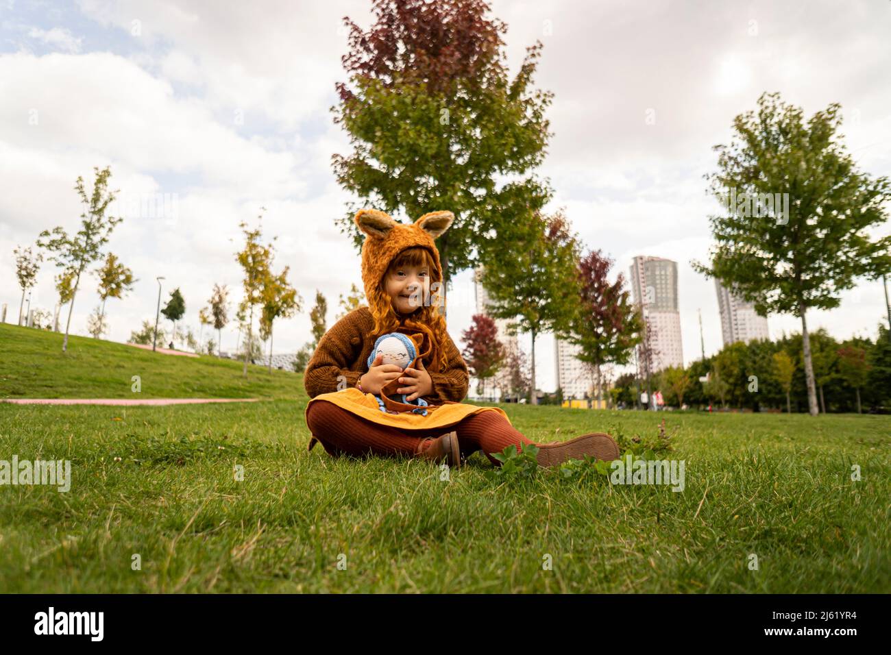 Girl with down syndrome sitting on grass in public park Stock Photo