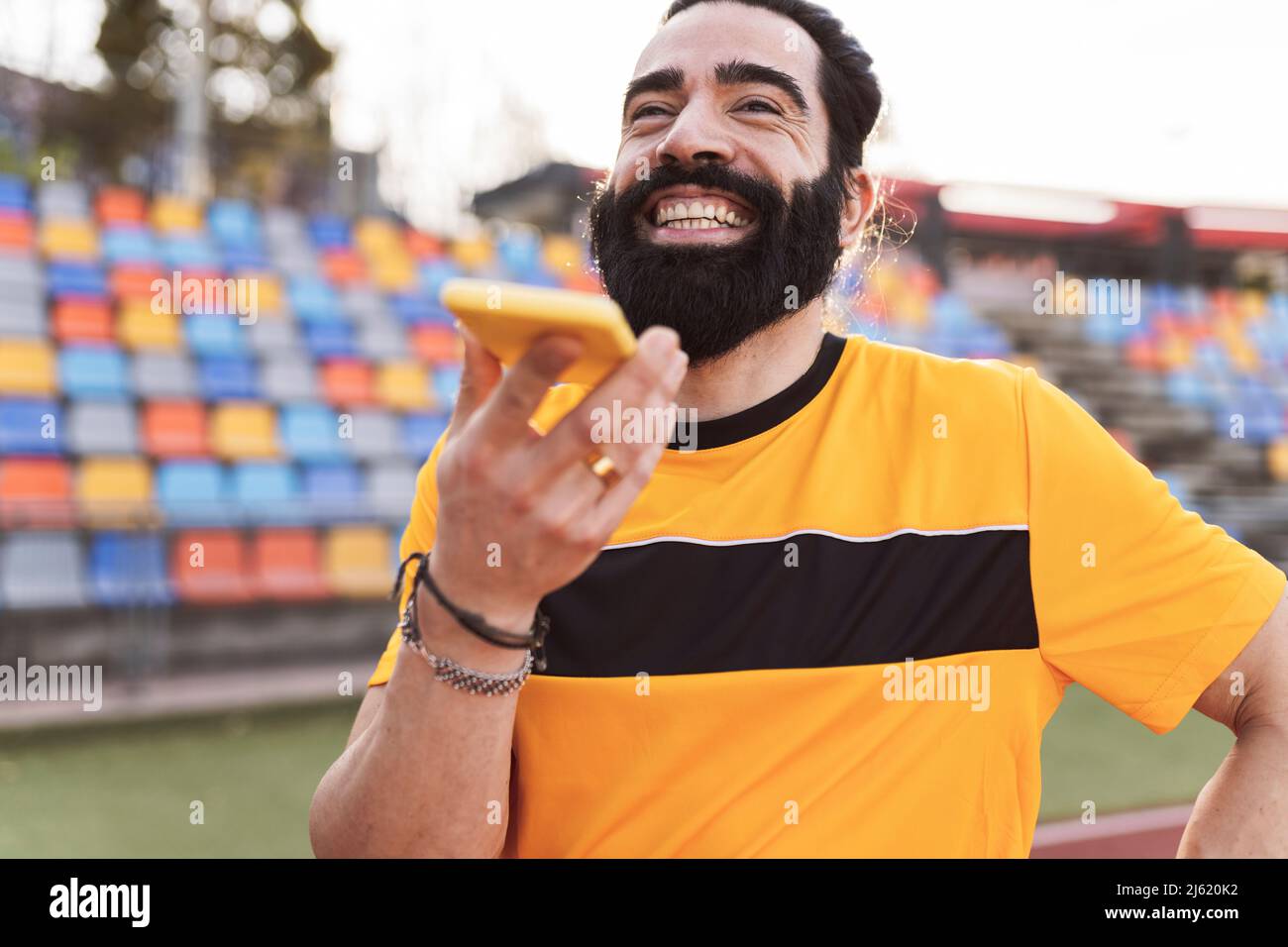 Happy bearded man talking on smart phone through speaker Stock Photo